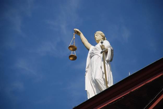 Statue of Lady Justice holding scales and a sword against a clear sky