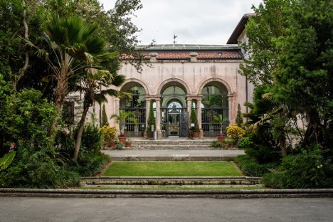 A stately building with arched entrances surrounded by greenery.