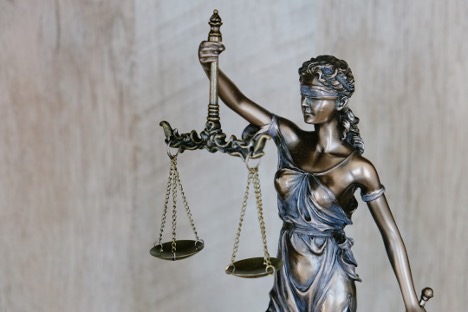 Close-up of Lady Justice holding scales in front of a courthouse.