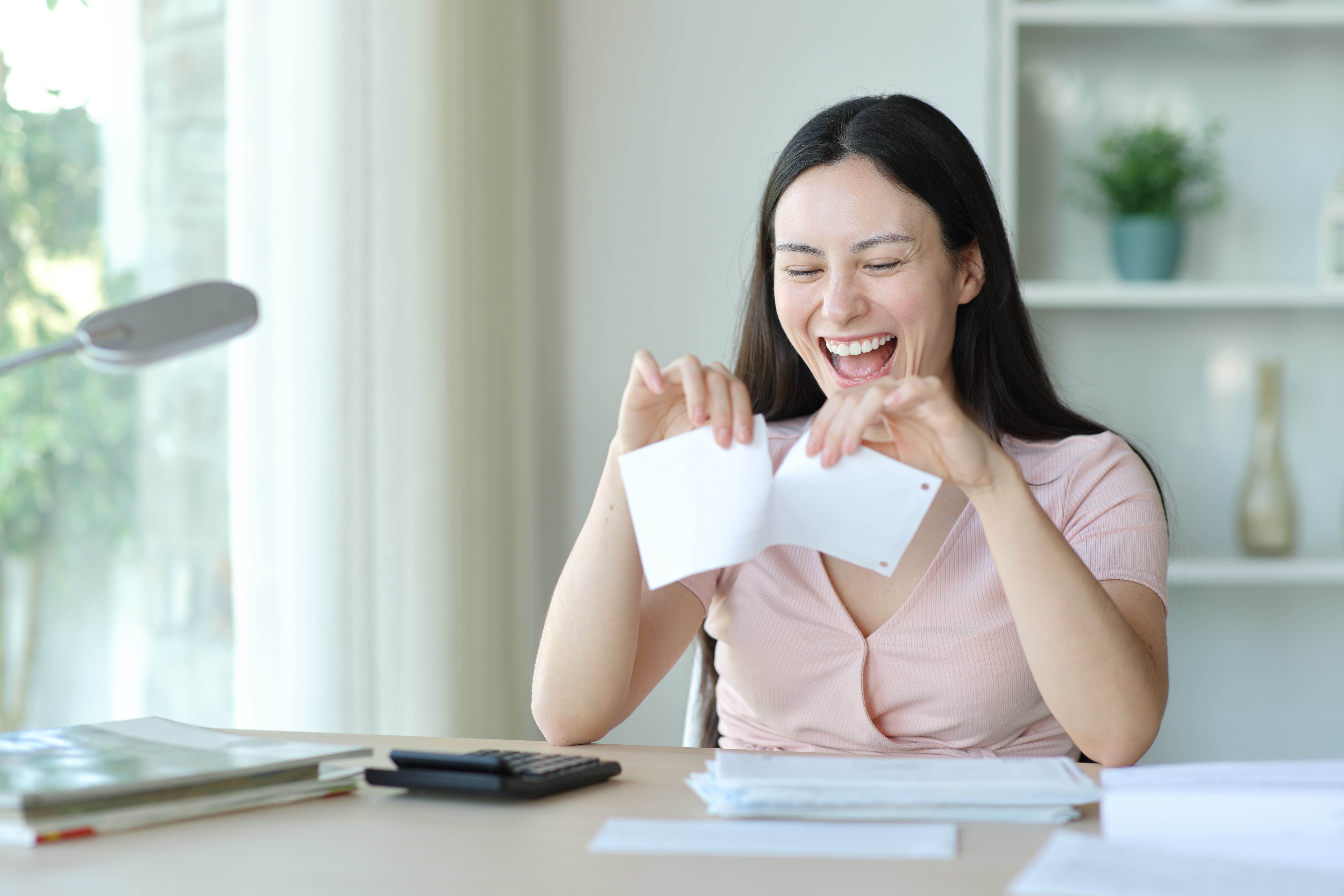 A happy woman tearing a document, representing relief after successfully breaking a lease without penalties.