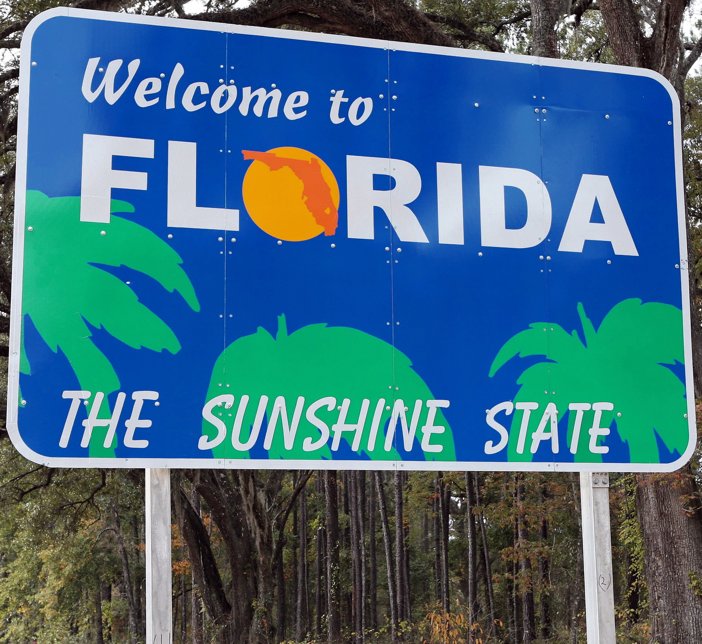 Welcome to Florida sign surrounded by palm trees, symbolizing the entry into Florida for new residents