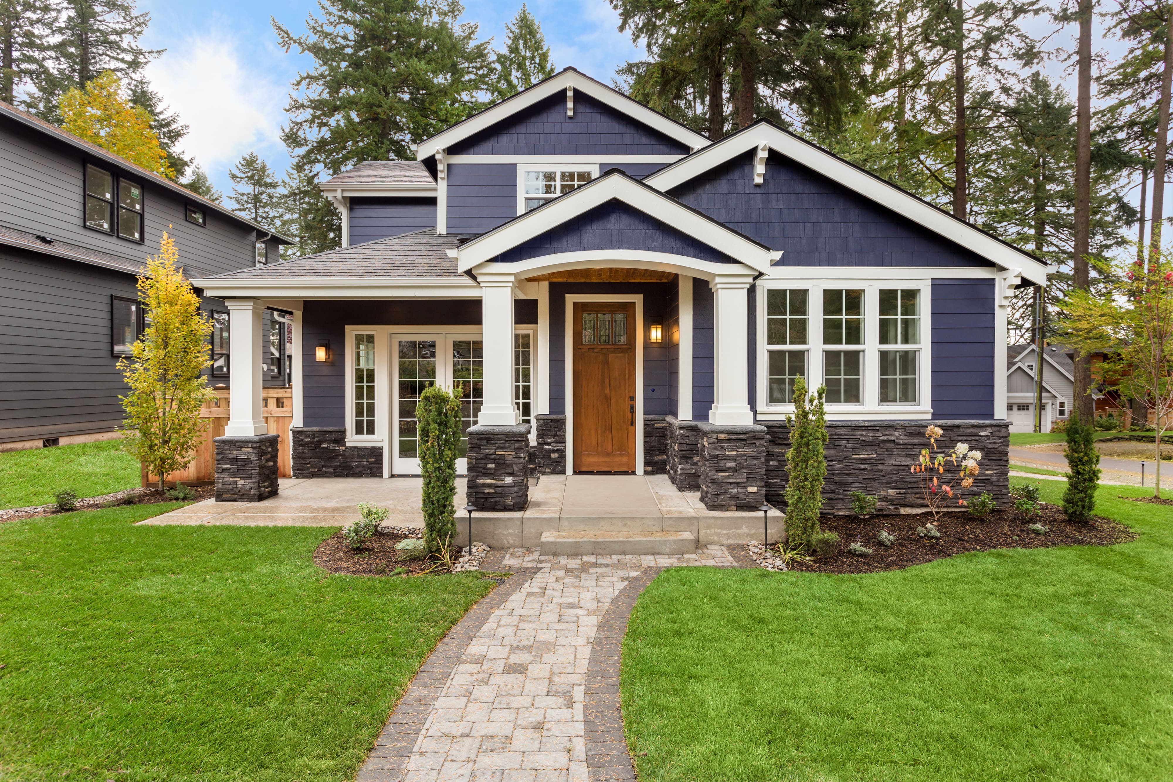 A modern single-family home with a navy blue exterior, white trim, and stone accents.