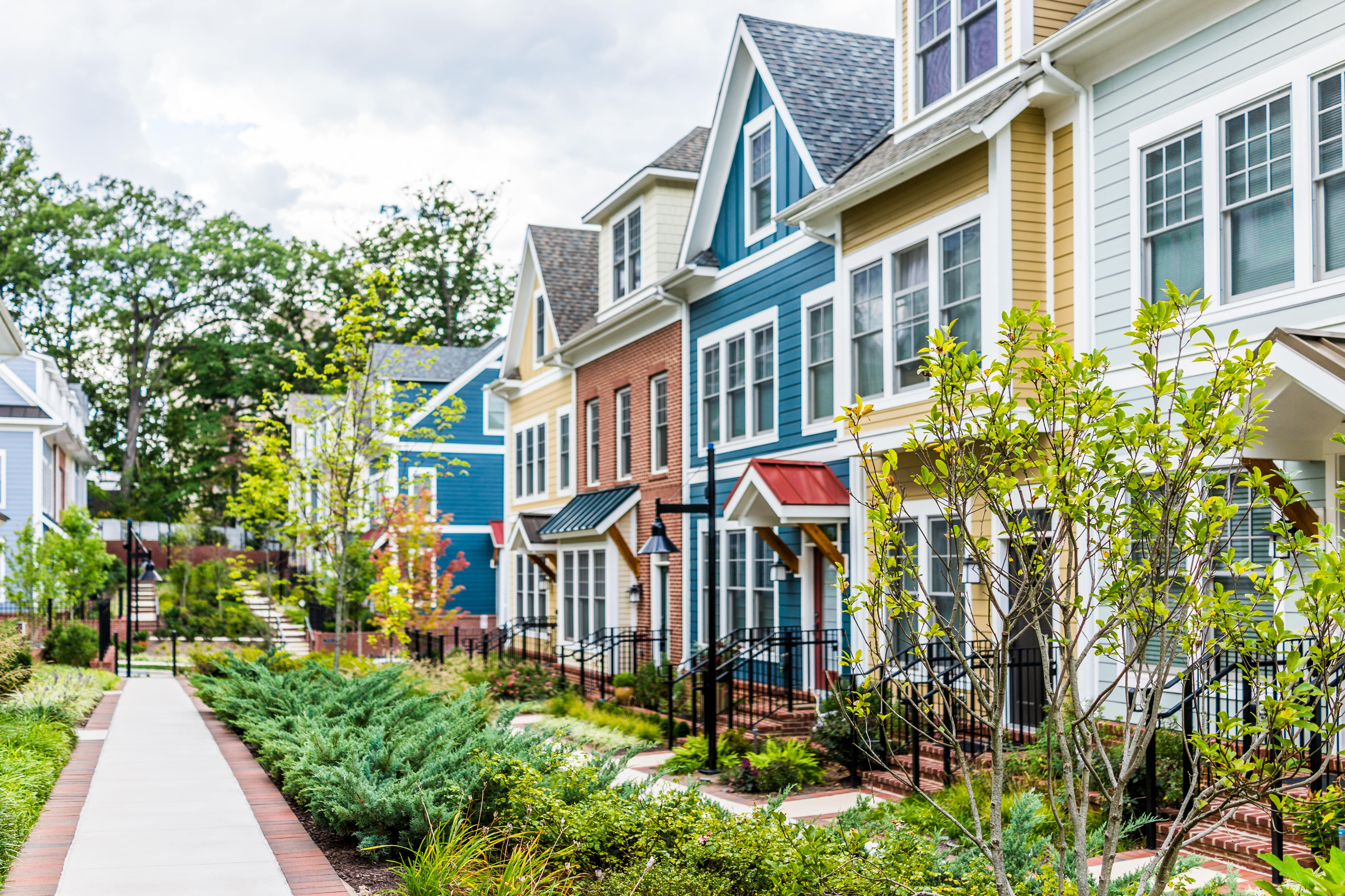 A charming row of colorful townhomes with lush landscaping along the pathway.