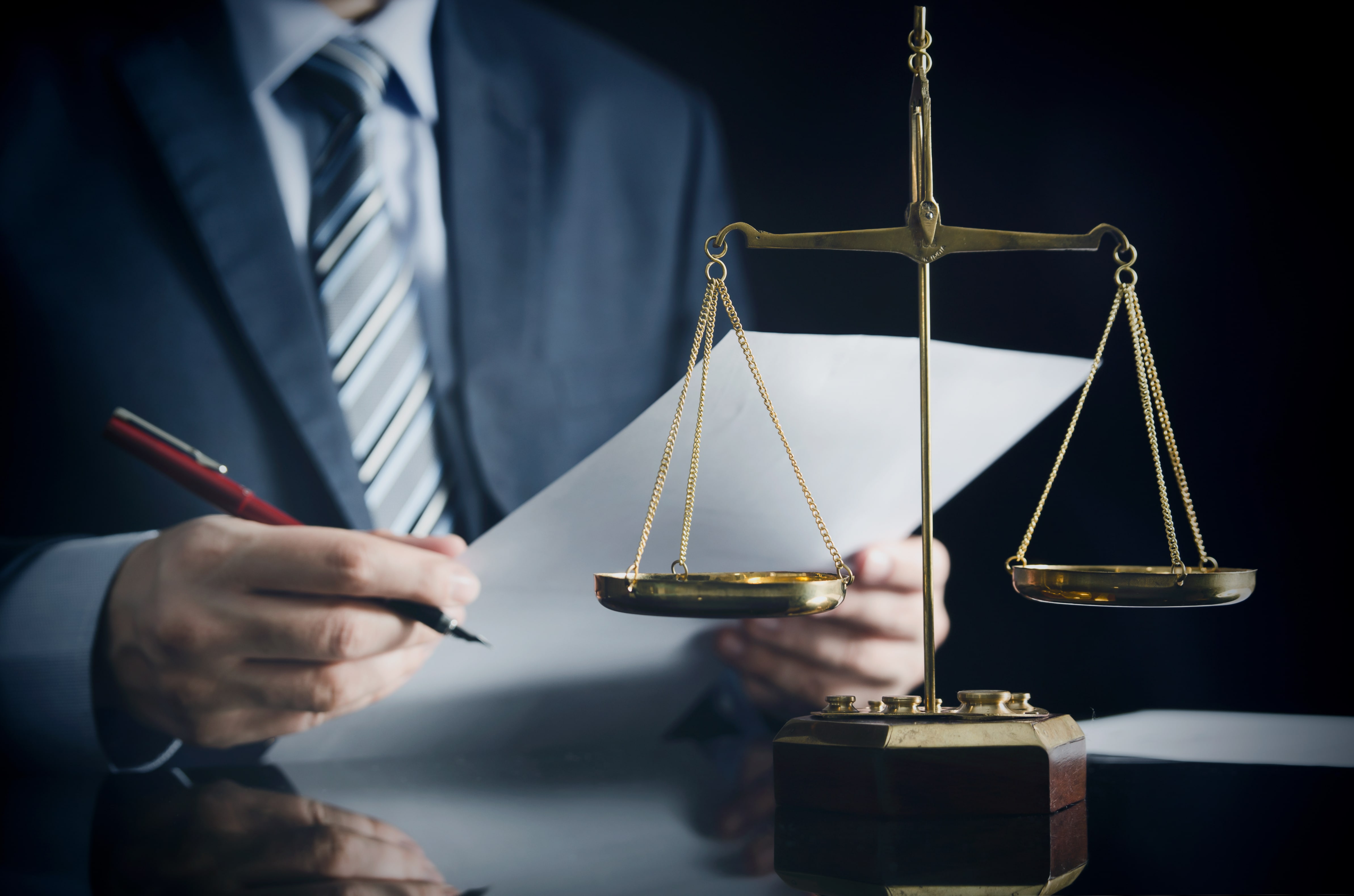 A businessman reviewing legal documents with a scale of justice in the foreground, representing the legal aspects of lease termination.