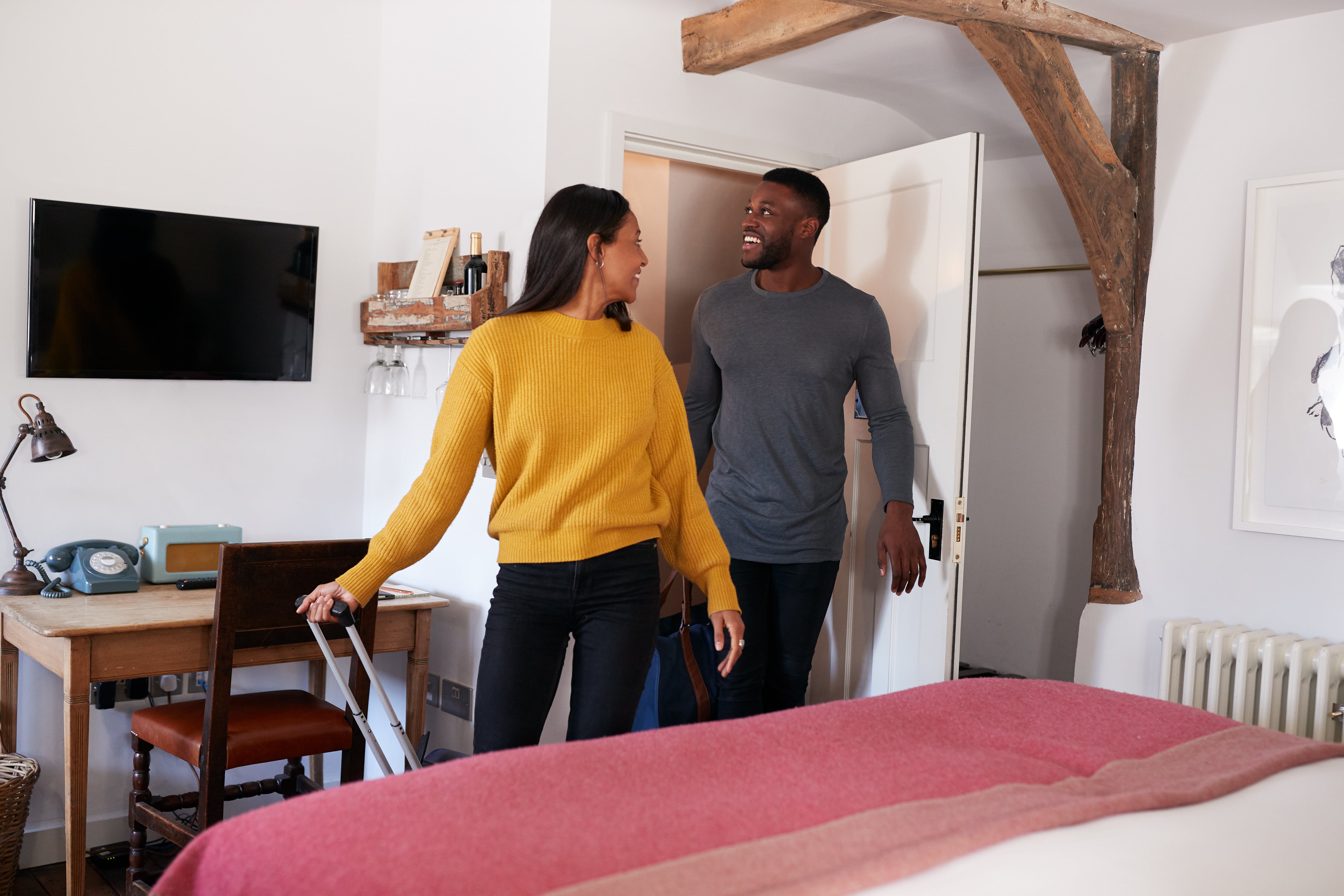 Smiling couple walking into a short-term rental with luggage—depicting the Airbnb guest experience.