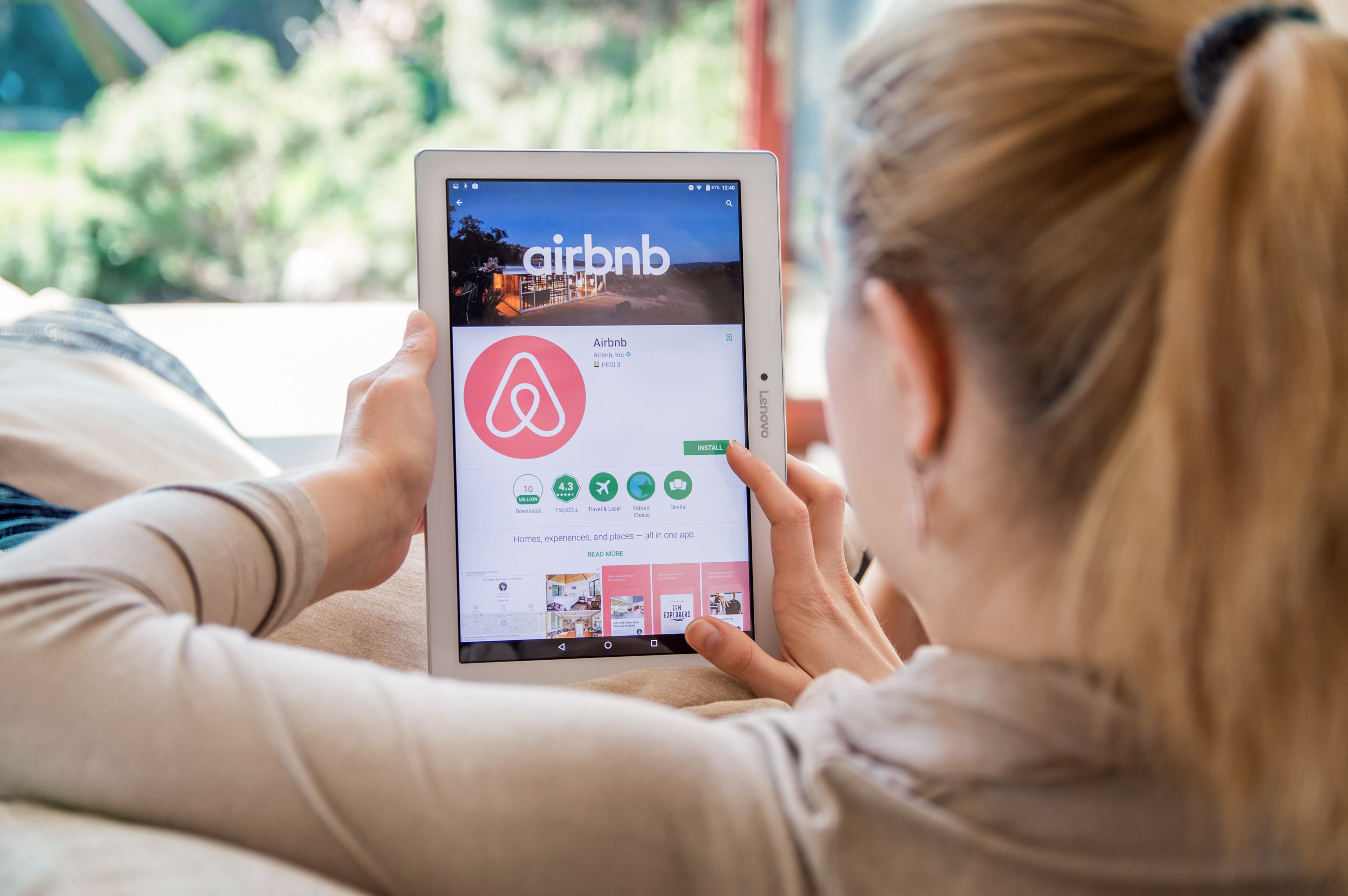 Woman browsing the Airbnb app on a tablet, representing short-term rental listing management.