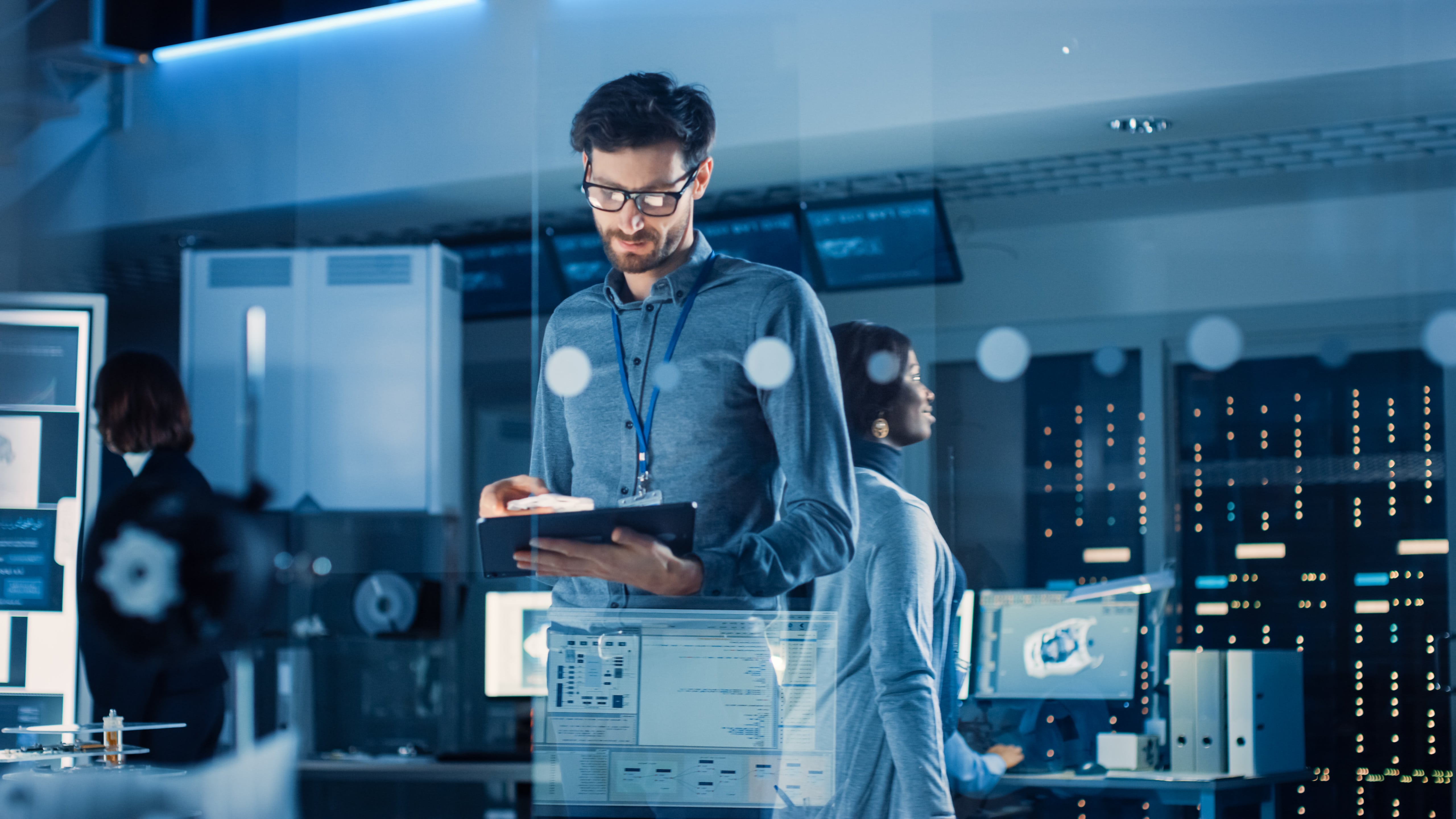 A man working in a high-tech office with digital screens and data visuals, representing the role of technology in modern real estate investing.