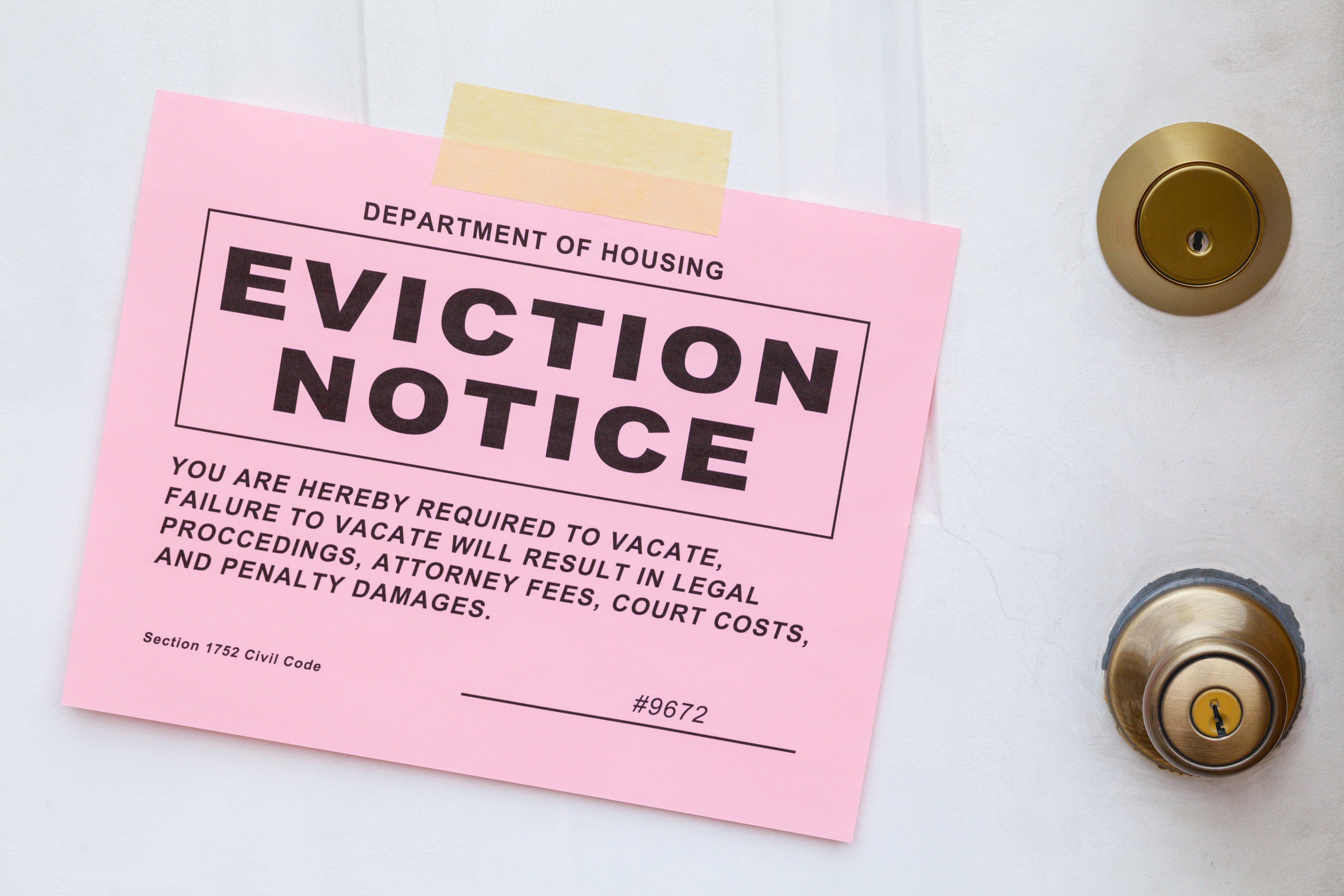 A pink eviction notice taped to a white door, notifying tenants of lease violations or legal action.