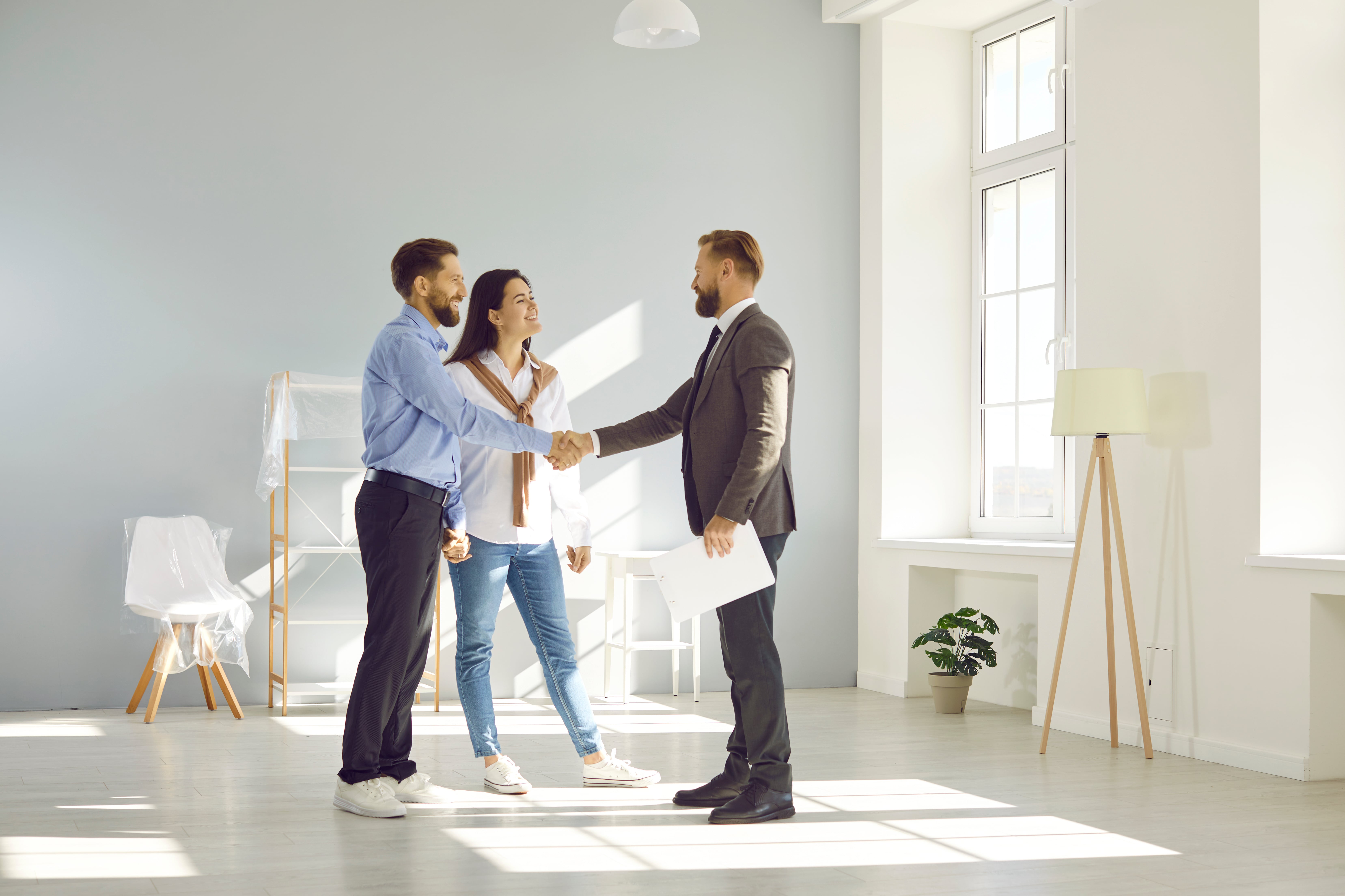 A property manager shaking hands with tenants inside a home, symbolizing negotiations or agreements when ending a lease early.