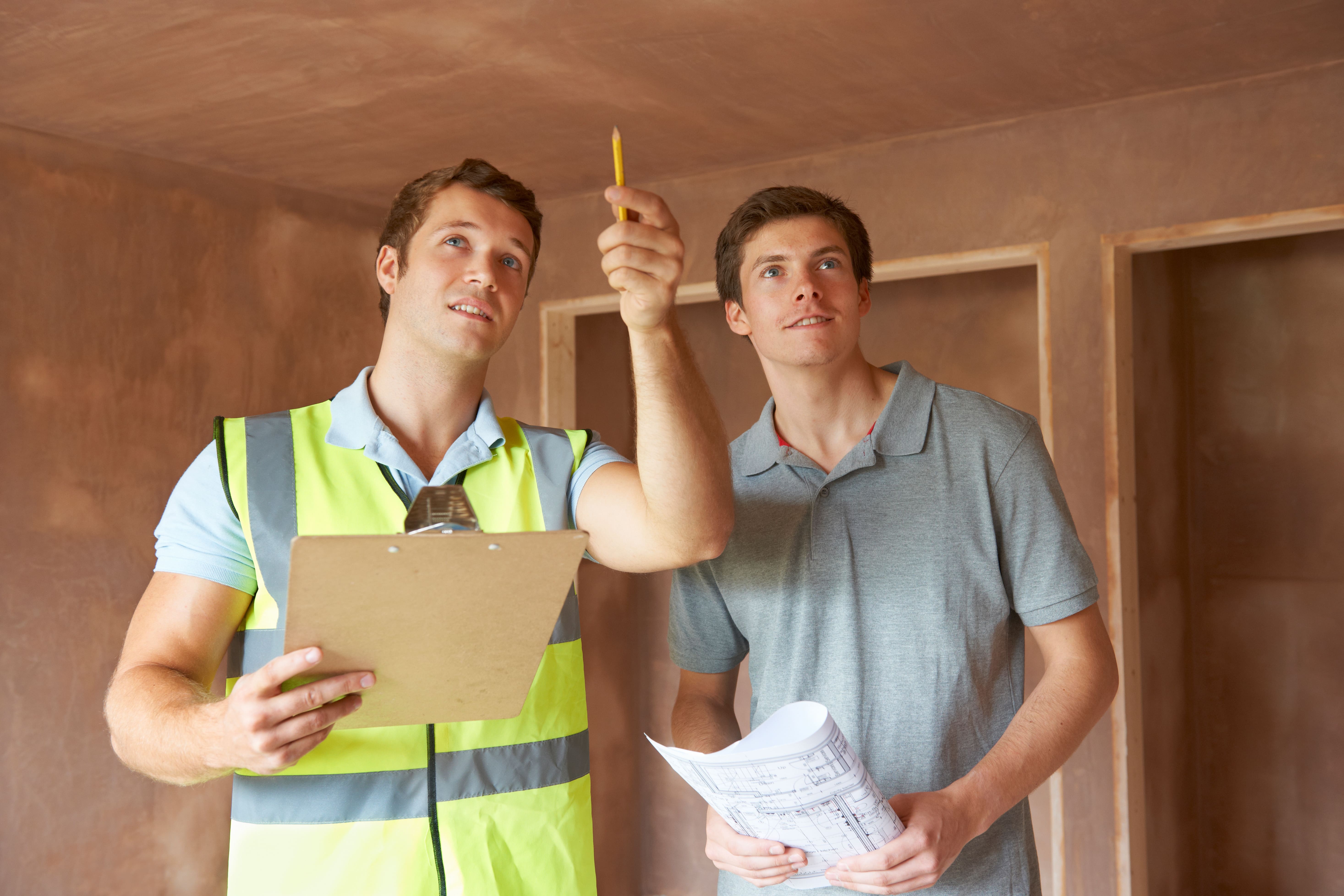 Two men conducting a property inspection; one in a high-visibility vest holding a clipboard, pointing upward while discussing with his colleague for flipping in Kissimmee, Florida