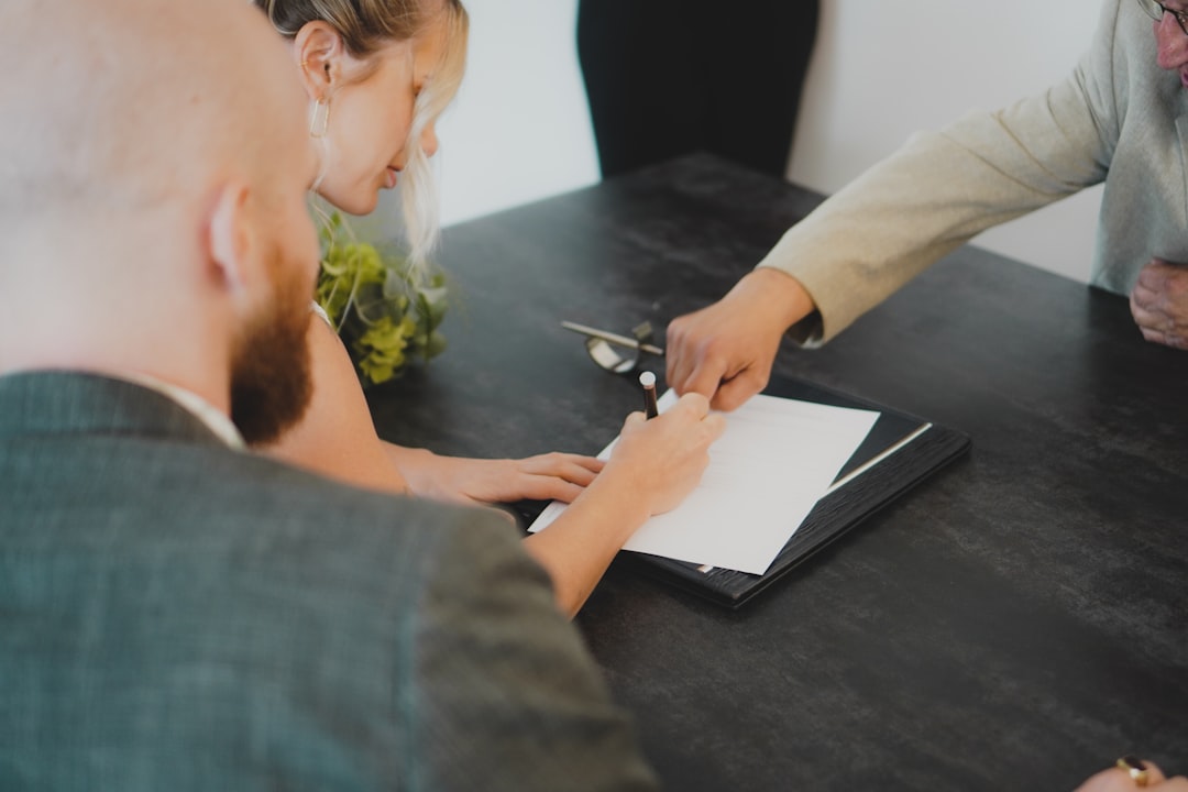 A group of people sitting at a table, signing documents during a formal meeting.