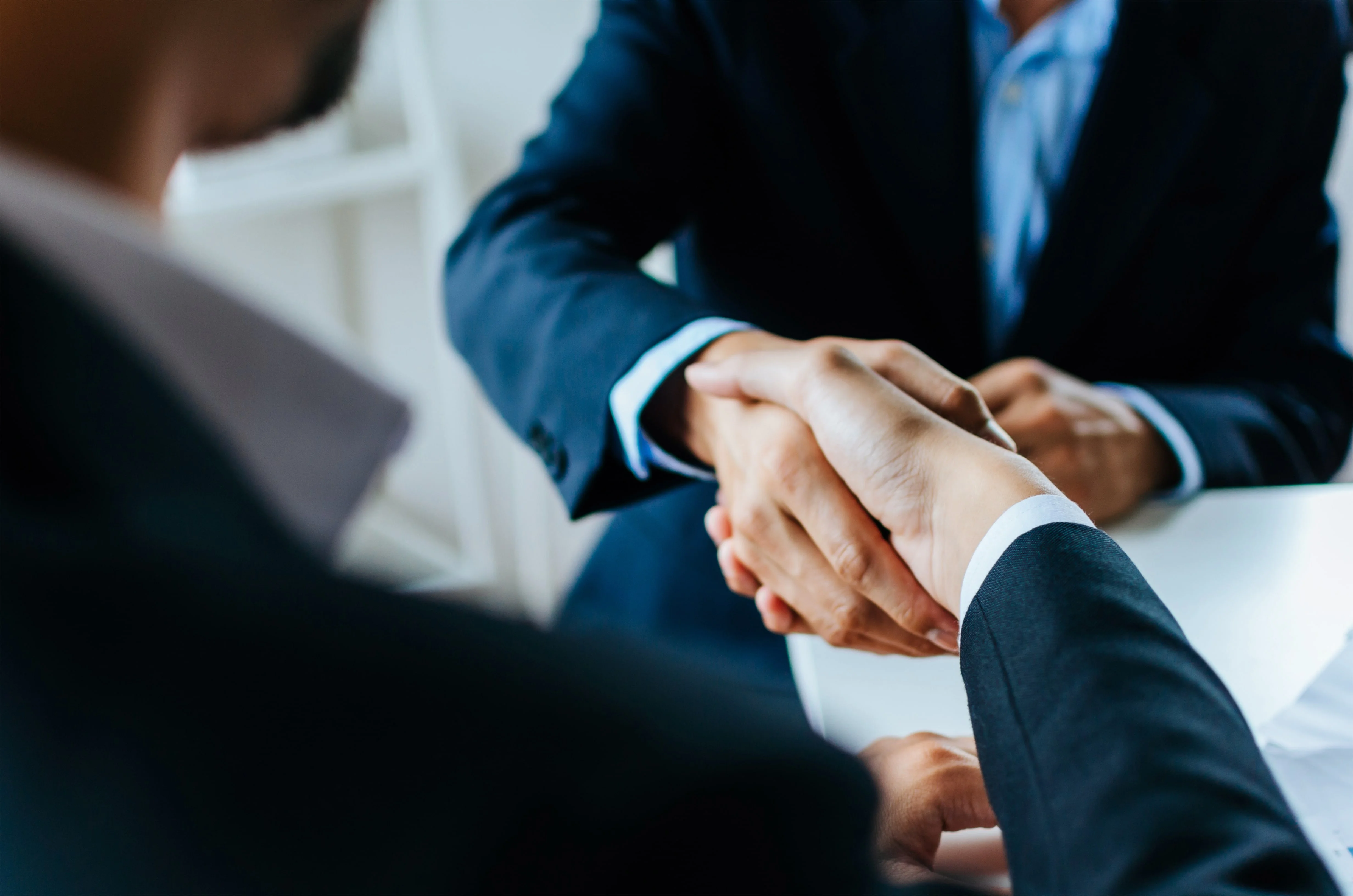 Two professionals shaking hands in business attire, representing property management partnership and rental agreement success.